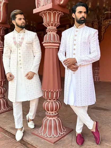 We create coordinated custom outfits for couples. Here, both grooms are in elegant white embroidered sherwanis, tailored for a perfect fit, ideal for a sophisticated wedding ceremony or a pre-wedding photoshoot.