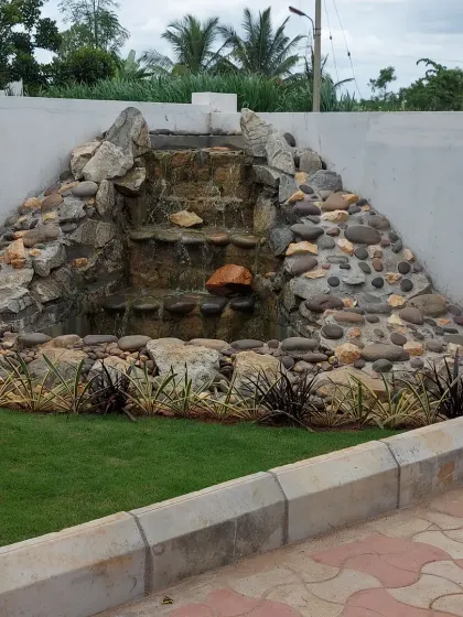 A custom-built rock waterfall feature against a boundary wall. This type of water feature can mask unwanted noise and create a soothing ambiance in any garden.