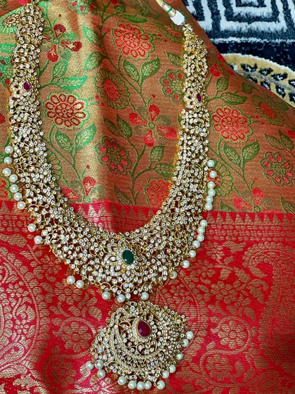 This stunning uncut diamond (polki) and pearl haram is perfect for a grand reception. The ruby pendant adds a pop of colour to this elegant piece.