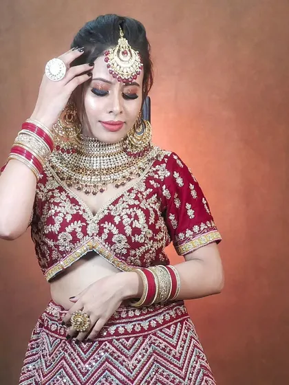 This bride is wearing a Polki choker set with red bead drops, perfectly matching her red embroidered blouse and chevron-patterned lehenga.