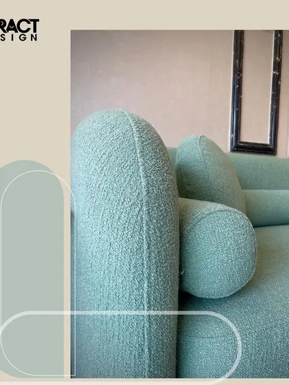A detail shot focusing on the arm and cushion shapes of our moss green "Cloud" sofa. The rounded forms and plush bouclé fabric invite you to sit back and relax.
