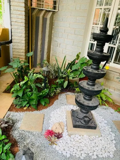 Another angle of the Deepa Stambha garden, showing the layout of the plants and hardscaping. The design creates a natural flow and highlights the traditional lamp post as the centerpiece.