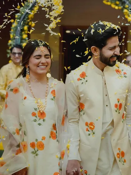 The couple's joyful entry at their Haldi ceremony, showered with yellow flower petals by their loved ones.