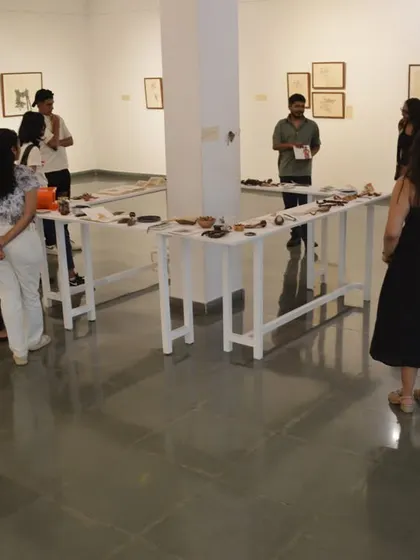 A group of visitors gathers around the installation tables as the artist, Mohit Mahato, gives a walkthrough of his work.