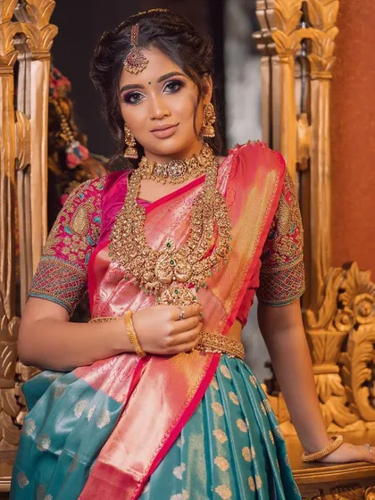 A lovely portrait of the model wearing this stunning teal and pink half saree. The gold jewelry provides the perfect traditional contrast.