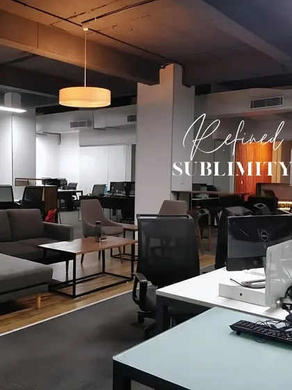 A refined and sublime office interior. The design uses a dark, exposed ceiling and a mix of task and ambient lighting to create a modern, industrial-chic workspace.