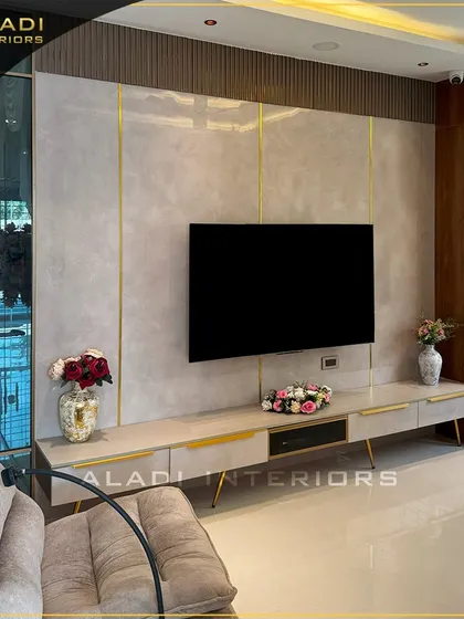 A luxurious TV wall unit design with a marble-finish back panel and gold inlay details. The low-profile console and elegant vases complete this sophisticated entertainment zone.