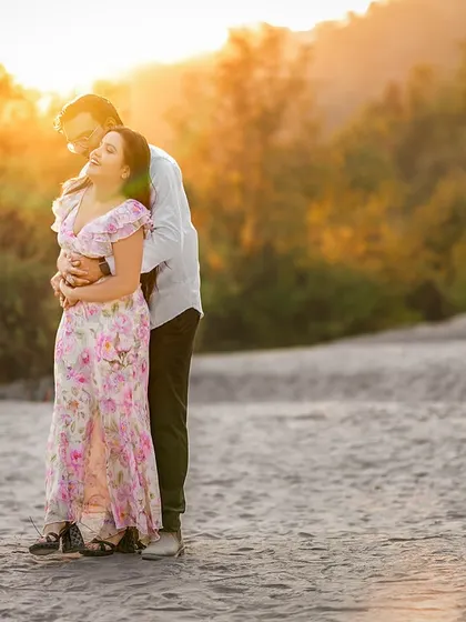 A moment of pure bliss. The sun's flare catches her hair as she leans back into his embrace, a perfect candid shot filled with warmth and affection.
