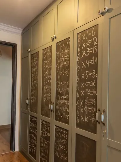 A creative storage solution for a kids' room, where some of the wardrobe doors are finished with chalkboard paint for doodling and learning.