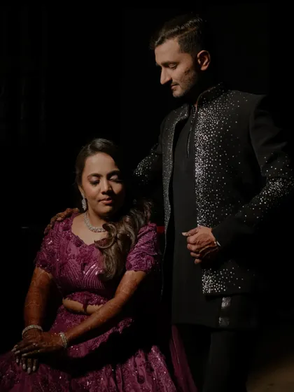 A quiet, intimate portrait of the couple away from the main stage. The low-key lighting creates a sense of closeness and romance, a calm moment in the midst of the party.