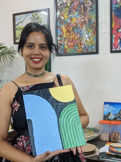 A participant proudly holding her finished texture painting, a beautiful piece with modern, abstract arches.
