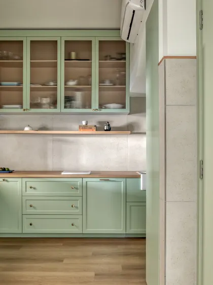 The kitchen was retrofitted into a small, preexisting room, so we focused on maximizing every inch. A light mint green color for the cabinetry and taking storage to the ceiling helps the compact space feel bright and spacious.