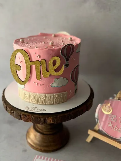 A lovely pink cake for a first birthday, decorated with hot air balloons and a glittering "One" topper. Firsts are always special.