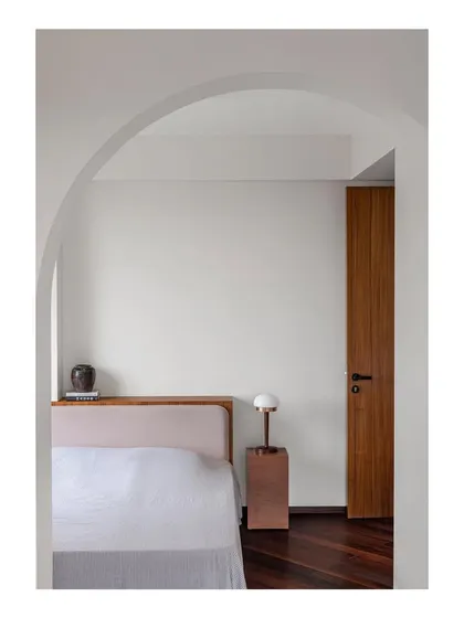 An archway functionally separates the sleeping and working zones in this bedroom while keeping them visually connected. This creates two distinct areas for rest and productivity within a single, cohesive space.
