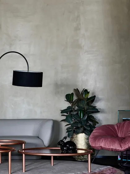 This vignette in the Ventura showroom combines a sleek modern sofa with a plush, velvet armchair. The lime-washed walls provide a neutral, textured backdrop for the furniture.