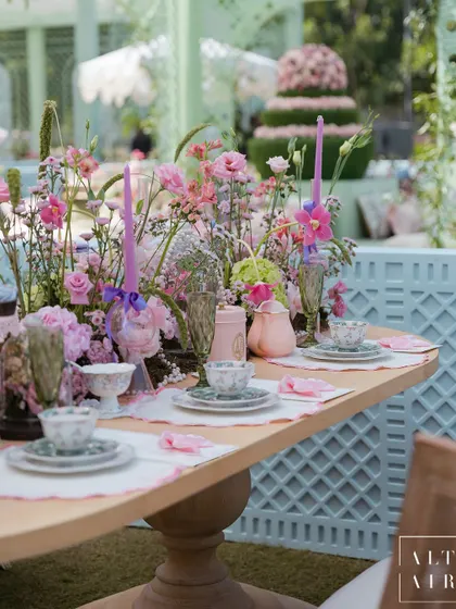 A beautiful tablescape from the 'Mayfair Luncheon', featuring floral-patterned china, pastel flowers, and elegant glassware. The setting was designed to feel like a garden tea party.