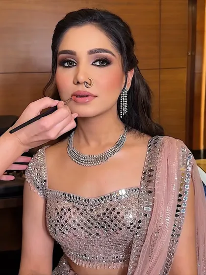 Final touches on a smokey eye and nude lip combination. The nose ring adds a traditional touch to this modern, glamorous party look.