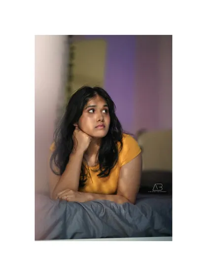 A soft and thoughtful portrait from the indoor series, capturing a moment of quiet contemplation on the bed.