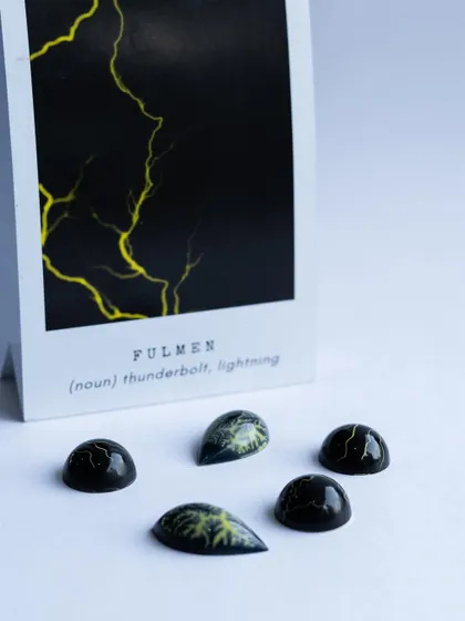 'Fulmen', meaning lightning. These bonbons capture the dramatic pattern of a thunderstorm using advanced airbrushing and coloring techniques taught in our chocolate classes.