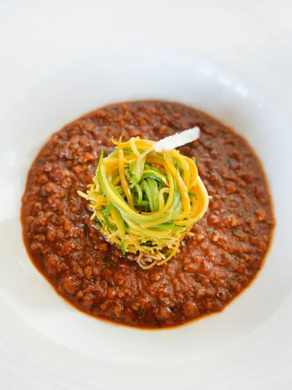 A closer look at the Chettinad chicken keema, topped with a nest of lemon and zucchini seviyan. The dish is layered with both depth and detail.