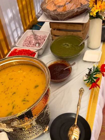 A close-up of a live counter setup for a government event. We use traditional brass and silver serveware for items like dal, accompanied by all the necessary condiments neatly arranged.