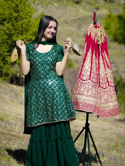A fun and creative pre-wedding shot, with the bride-to-be holding her shoes next to her beautiful red lehenga.