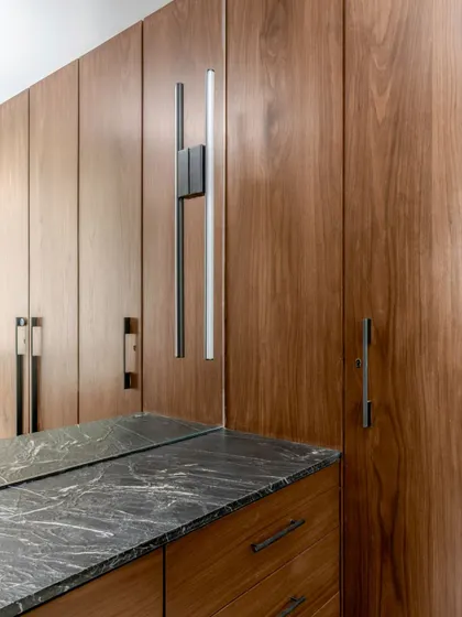 Detail of a custom wardrobe in the Parishram residence. The combination of dark wood and a black marble top, along with sleek, modern hardware, exemplifies our commitment to material honesty.