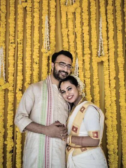 This portrait captures the couple in a tender embrace in front of a traditional yellow flower curtain. Their calm smiles and traditional attire create a picture of serene togetherness.