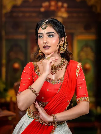 A model posing in the red and off-white lehenga, showcasing its elegant design.