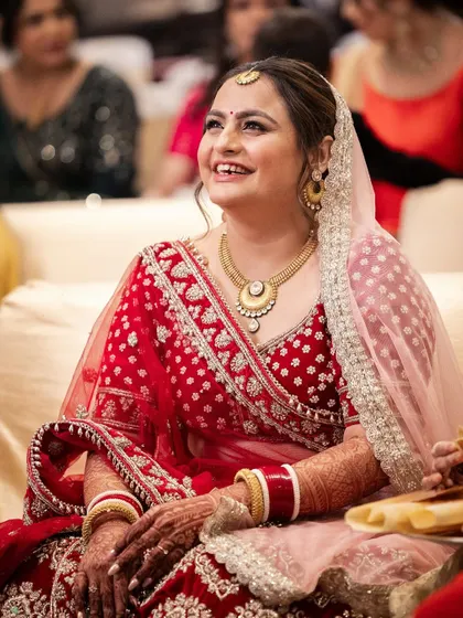 The sweetest bride Rashi, smiling during her wedding ceremony. Her makeup is soft and romantic, with a focus on a clean base and rosy cheeks.