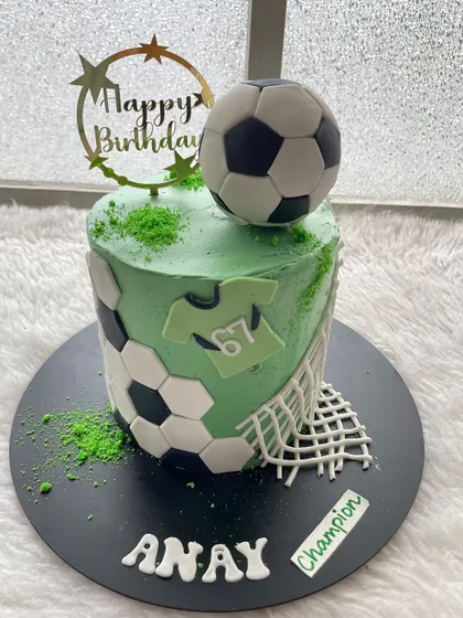 A football-themed cake with a vibrant green field, a net, and a big soccer ball on top. Perfect for a champion's birthday.