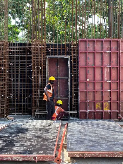Workers preparing the steel formwork and rebar cage for an in-situ concrete wall at the farmhouse site.
