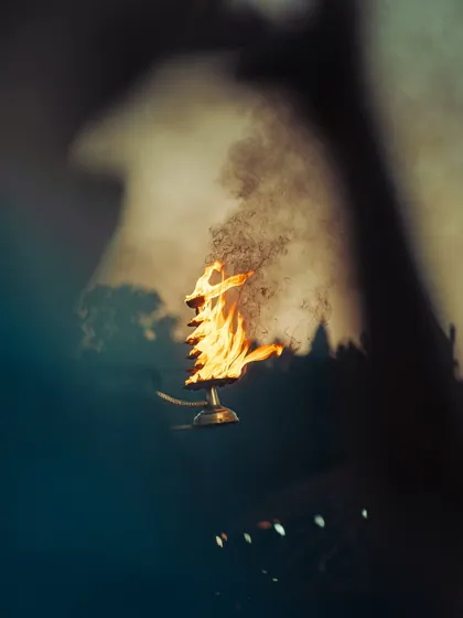 An abstract and artistic shot of the sacred fire used in the Ganga Aarti. The focus on the flame and smoke creates a powerful and symbolic image.