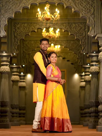 A full-length shot of the couple in traditional wear, posing in a grand, palace-like corridor. This showcases the elegance of the location and outfits.