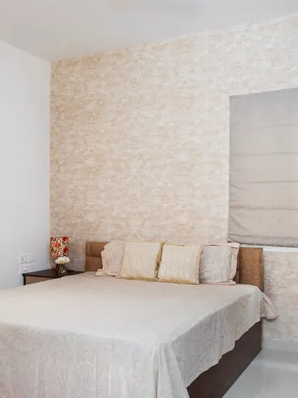 This bedroom uses soft neutrals and cozy textures to create a calm and inviting feel. The textured wallpaper behind the bed adds subtle interest without overwhelming the space.