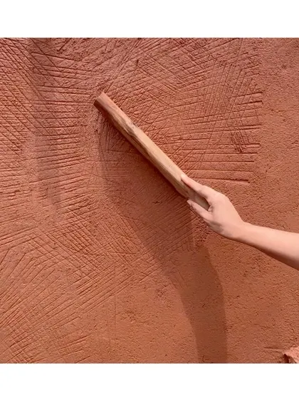 A close-up of the wooden 'Thappi' tool creating its signature strokes on the wall. This is a time-honored technique that we are passionate about preserving.