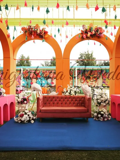 The main stage of the carnival-themed Mehendi, featuring bright orange arches and whimsical flamingo props.