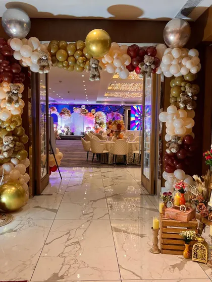 The entrance to a baby shower, framed by a beautiful balloon arch with small teddy bears tucked into the arrangement.