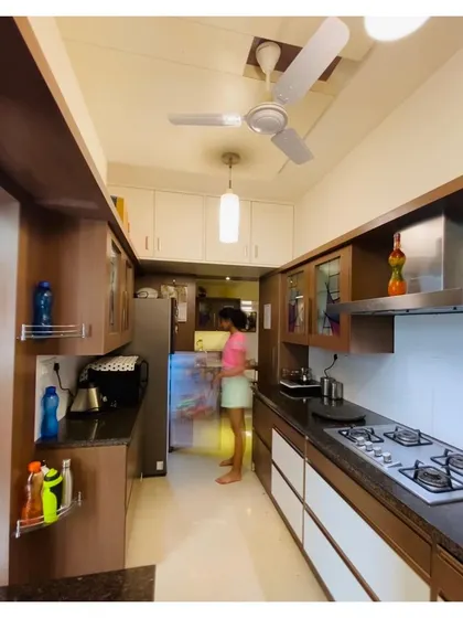 The galley kitchen in the Malhotra Apartment, designed for maximum efficiency and storage. We used a two-tone cabinet system with wood and white finishes to create a visually larger and brighter kitchen.