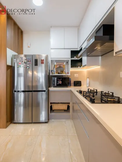 A compact and efficient L-shaped kitchen design. We integrated the microwave and refrigerator into the cabinetry for a clean, built-in look, proving that great design can work in any space.