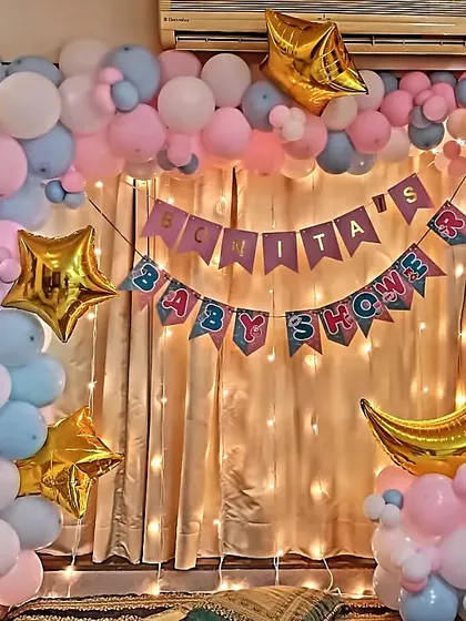 A simple yet beautiful backdrop for an at-home baby shower. I created a balloon frame with pastel pink and blue balloons, accented with gold stars and a curtain of fairy lights.