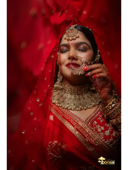 A stunning close-up of the bride under her red veil, capturing her beautiful makeup and jewelry.