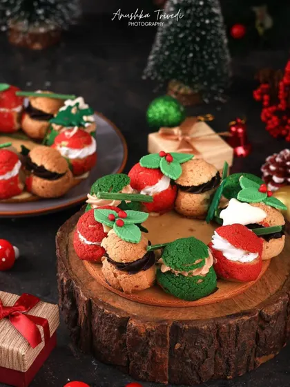 A festive wreath made of cream puffs, decorated with red and green colors and holly leaves for a unique Christmas dessert idea.