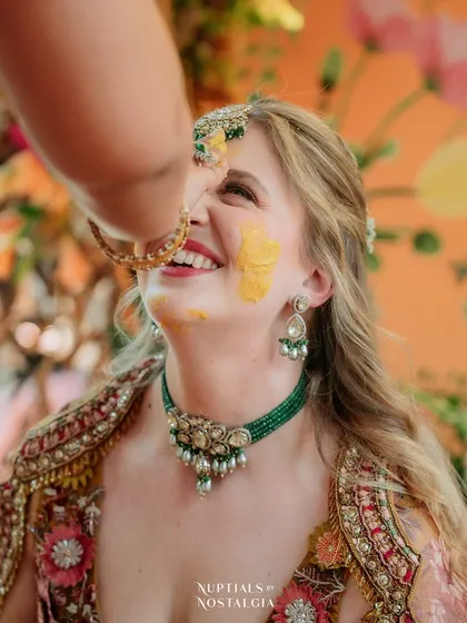 A close-up of Alex's joyful expression as turmeric is applied to her face, showing her full immersion in the cultural experience.