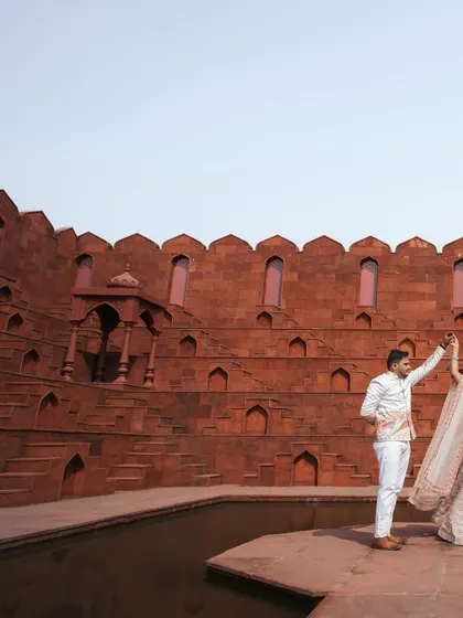 A dynamic shot of the couple dancing at the base of a historic step-well, with the expansive red walls creating a breathtaking backdrop for their pre-wedding photo.