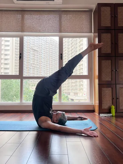 A student celebrates International Yoga Day with a joyful expression of Salamba Sarvangasana (Shoulder Stand).