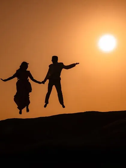 A playful silhouette of a couple jumping against the setting sun. This shot is full of energy and joy, a perfect memory of their pre-wedding adventure.