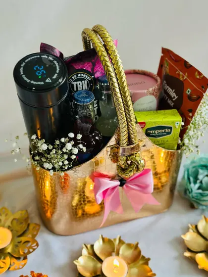 A stunning Diwali hamper in a metallic basket, surrounded by lit diyas. A perfect centerpiece for a festive celebration.