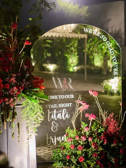 A personalized welcome sign for Mitali and Arjun's cocktail night. The mirrored arch reflects the surrounding garden, while the elegant script and floral accents create a warm and personal greeting for every guest.