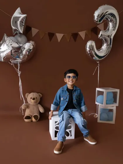 A full view of the stylish third birthday setup. The combination of silver balloons and a neutral backdrop is perfect for a modern toddler shoot.